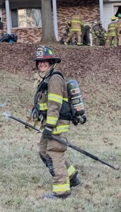 firefighter in full uniform walking away from the camera, smiling back.